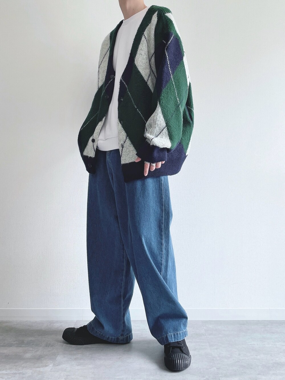 グリーン系のカーディガン/ボレロ、ホワイト系のトップス、ブルー系のデニムパンツを着用したメンズの秋コーディネートの3枚目の写真