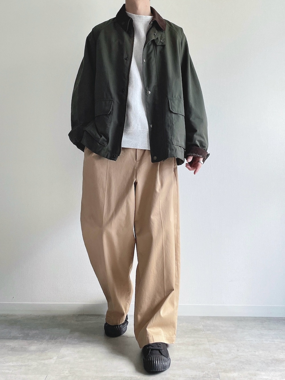 グリーン系のミリタリージャケット、グレー系のトップス、ベージュ系のチノパンツを着用したメンズの冬コーディネートの2枚目の写真
