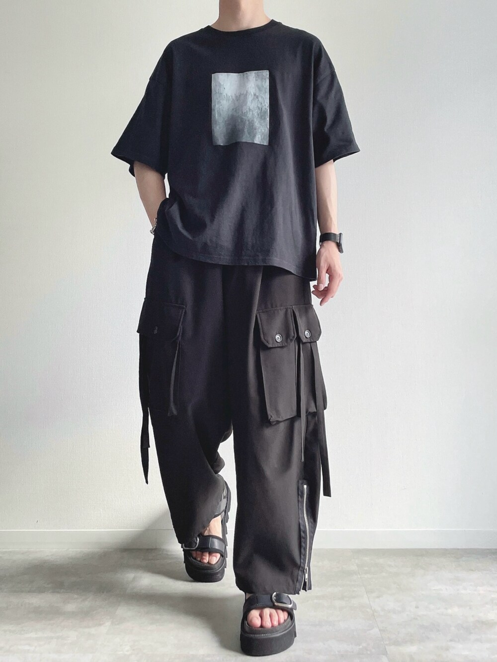 ブラック系のTシャツ/カットソー、ブラック系のカーゴパンツ、ブラック系のサンダルを着用したメンズの夏コーディネートの2枚目の写真