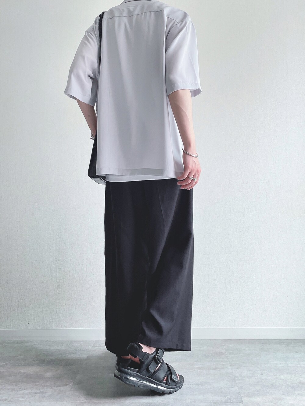 グレー系のトップス、ホワイト系のタンクトップ、ブラック系のスラックスを着用したメンズの夏コーディネートの4枚目の写真