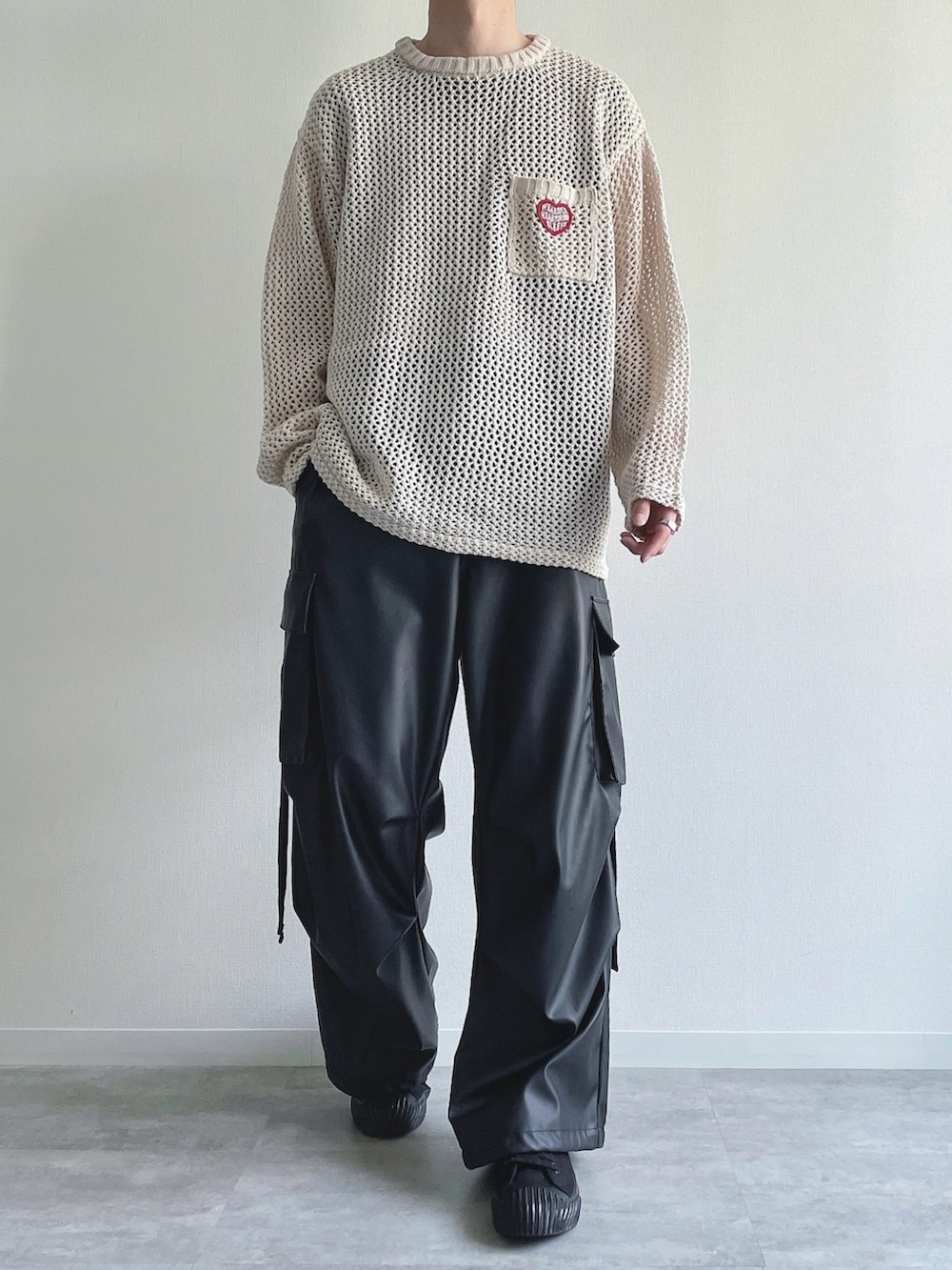 ホワイト系のニット/セーター、ブラック系のTシャツ/カットソー、ブラック系のカーゴパンツを着用したメンズの春コーディネートの2枚目の写真