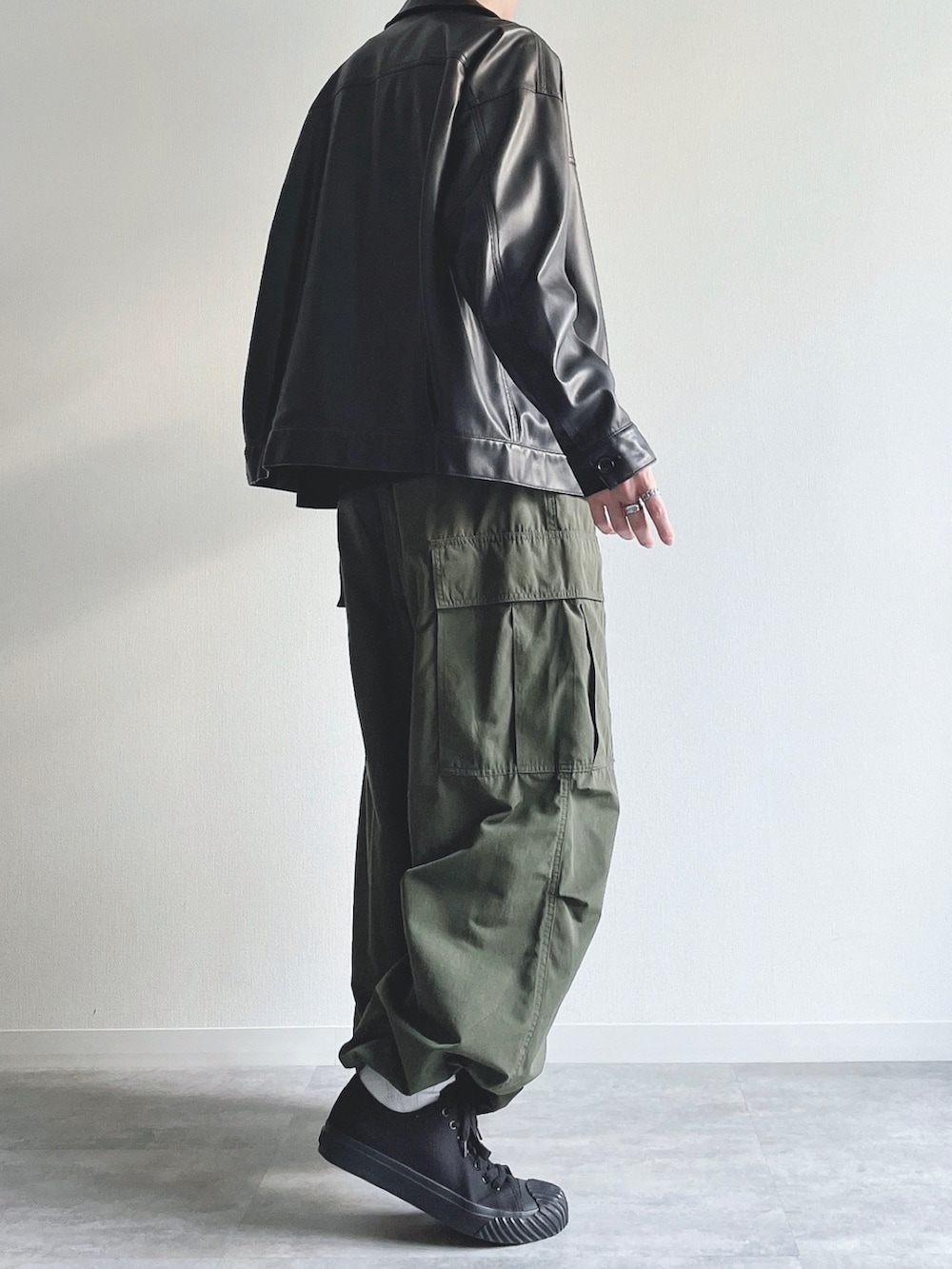 ブラック系のブルゾン、ブラック系のTシャツ/カットソー、グリーン系のカーゴパンツを着用したメンズの秋コーディネートの4枚目の写真