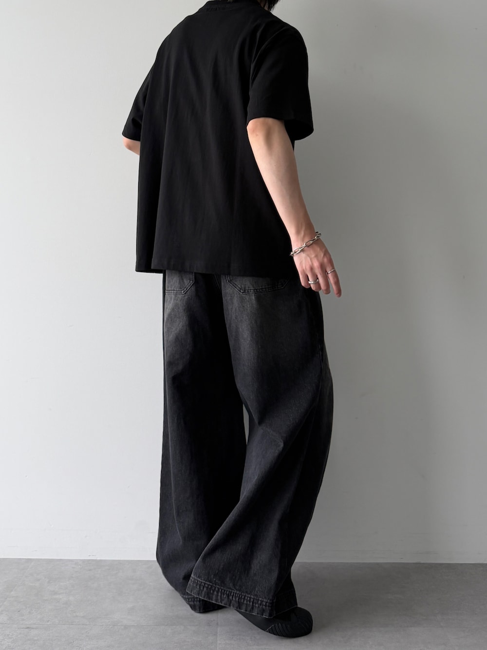 ブラック系のデニムパンツ、ブラック系のTシャツ/カットソー、ブラック系のスニーカーを着用したメンズの春コーディネートの4枚目の写真
