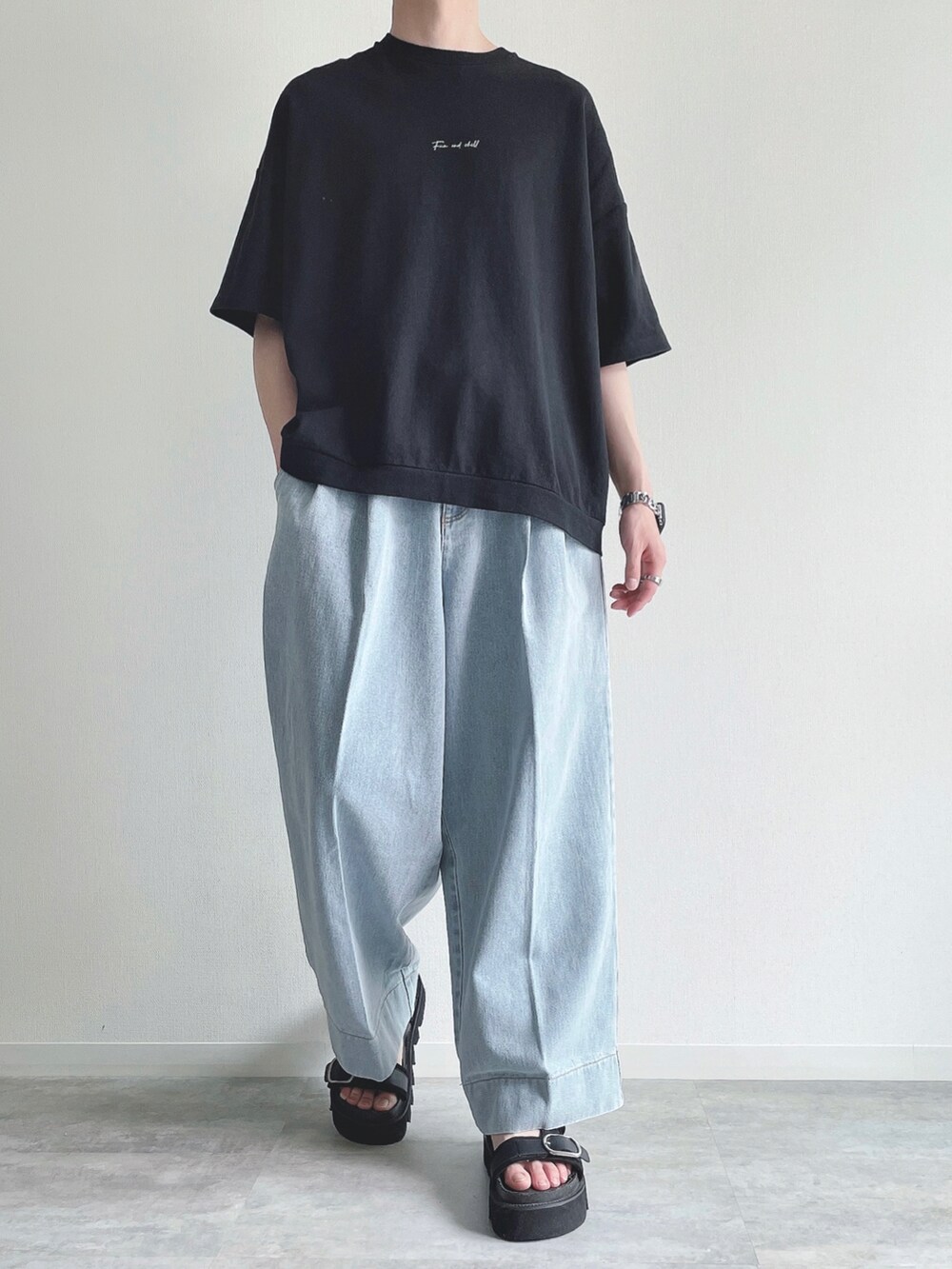 ブラック系のTシャツ/カットソー、ブルー系のデニムパンツ、ブラック系のサンダルを着用したメンズの夏コーディネートの2枚目の写真