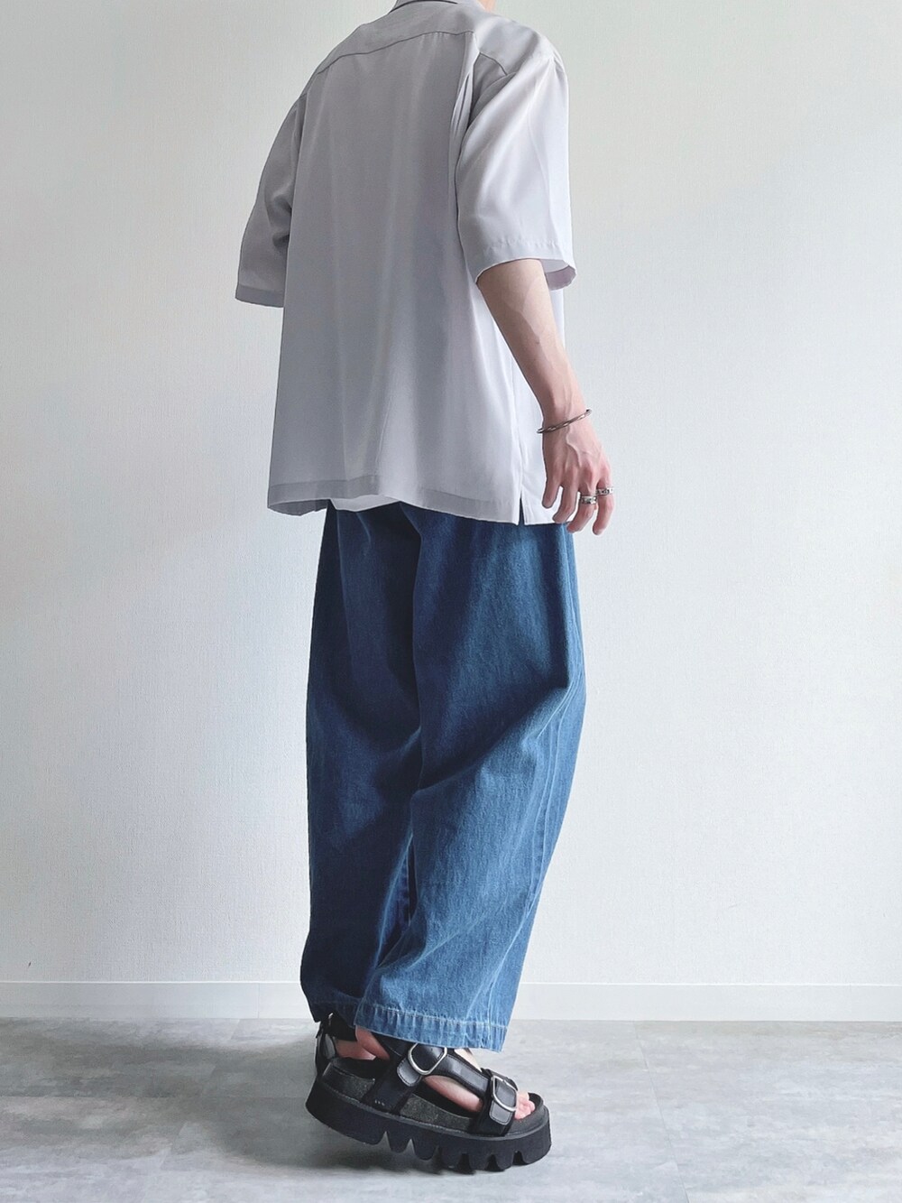 グレー系のトップス、ホワイト系のタンクトップ、ブルー系のデニムパンツを着用したメンズの夏コーディネートの4枚目の写真