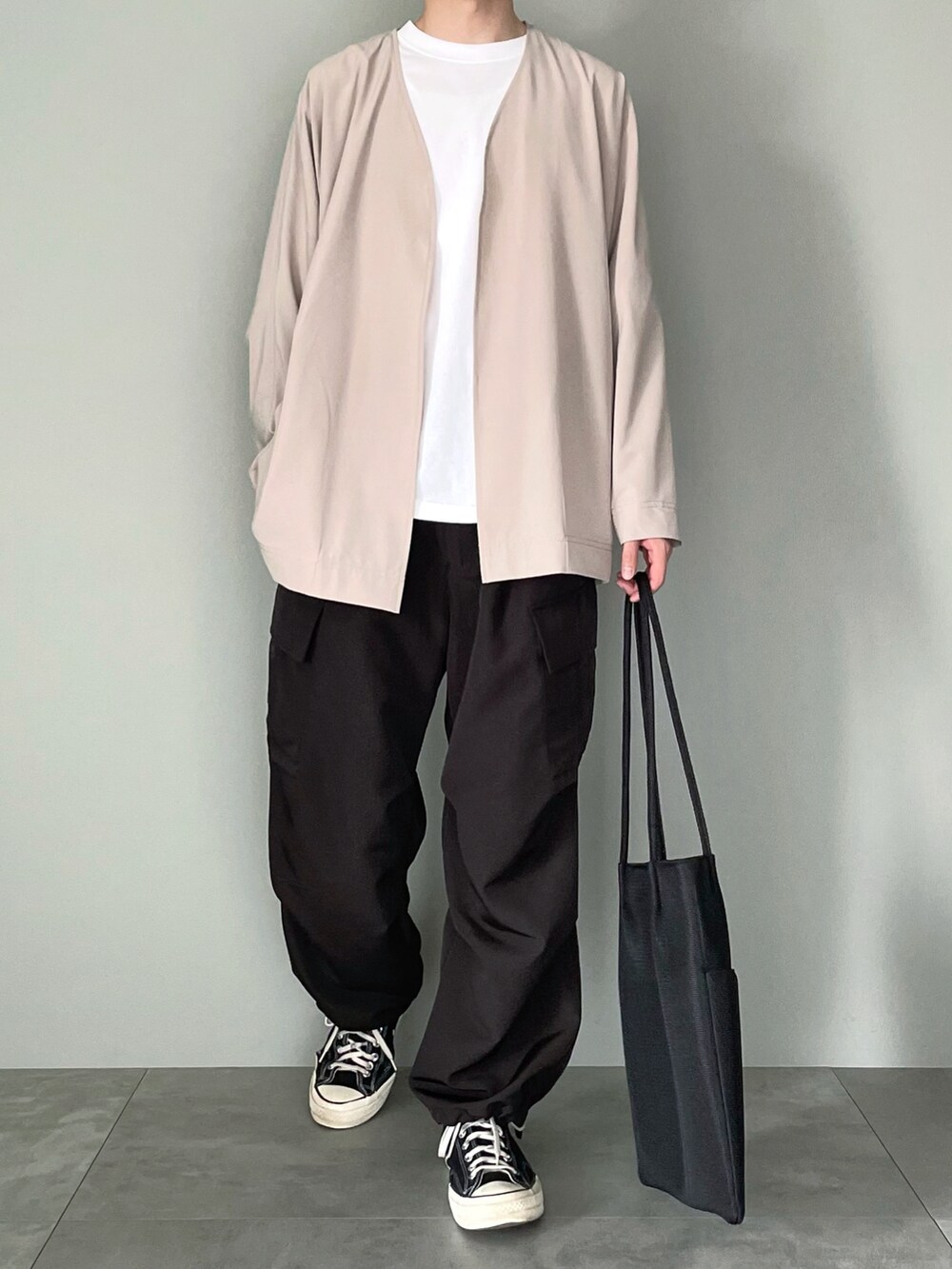 ベージュ系のカーディガン/ボレロ、ホワイト系のTシャツ/カットソー、ブラック系のカーゴパンツを着用したメンズの春コーディネートの2枚目の写真