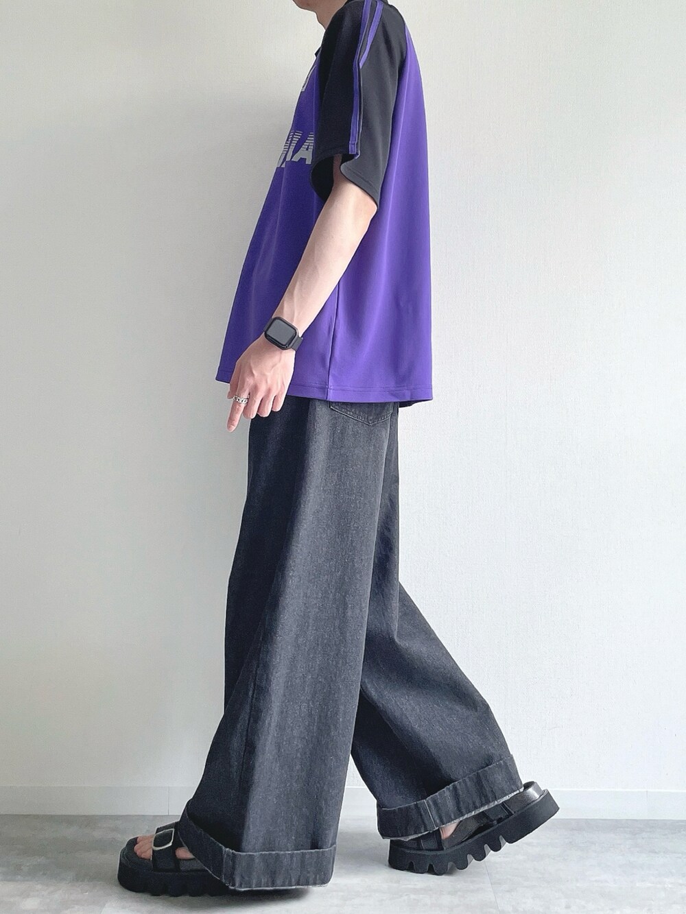 パープル系のTシャツ/カットソー、ブラック系のデニムパンツ、ブラック系のサンダルを着用したメンズの夏コーディネートの3枚目の写真