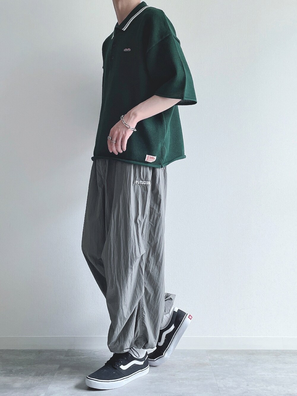 グリーン系のポロシャツ、グレー系のその他パンツ、ブラック系のスニーカーを着用したメンズの夏コーディネートの3枚目の写真