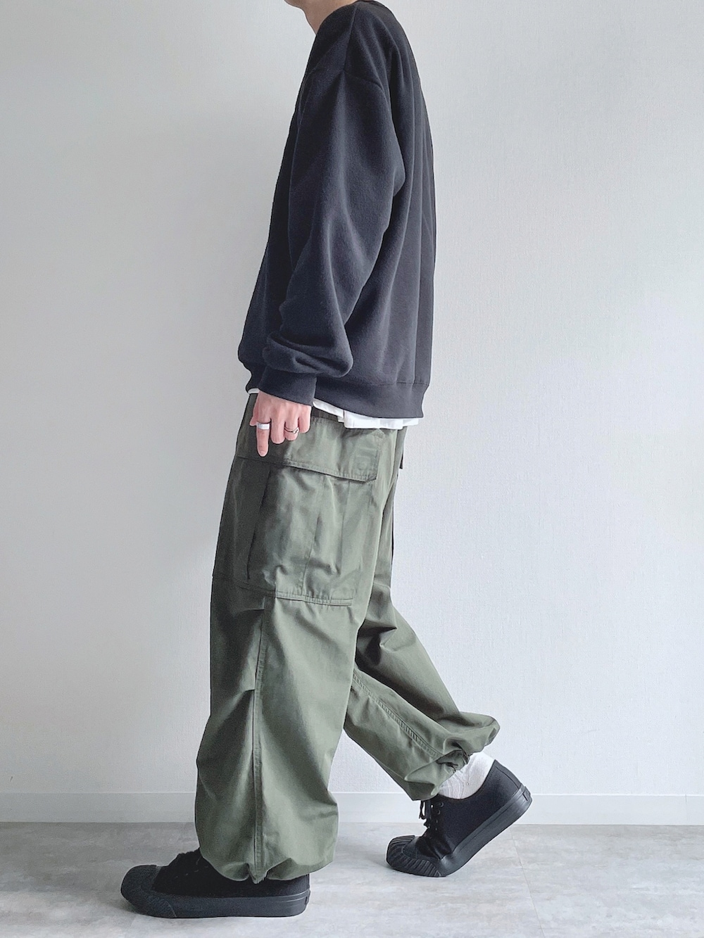 ブラック系のスウェット、ホワイト系のTシャツ/カットソー、グリーン系のカーゴパンツを着用したメンズの春コーディネートの2枚目の写真