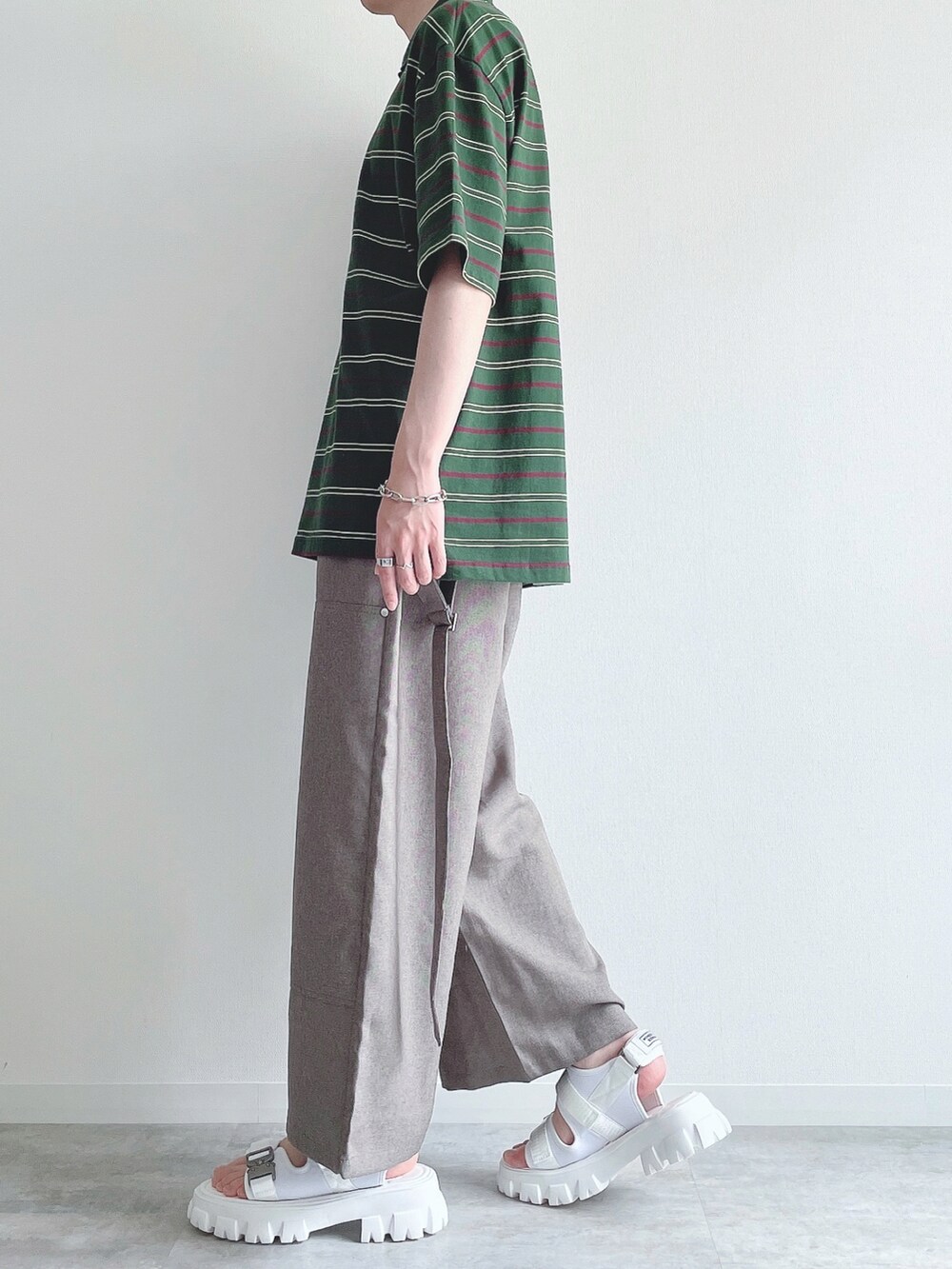 グリーン系のトップス、ベージュ系のスラックス、ホワイト系のサンダルを着用したメンズの夏コーディネートの3枚目の写真