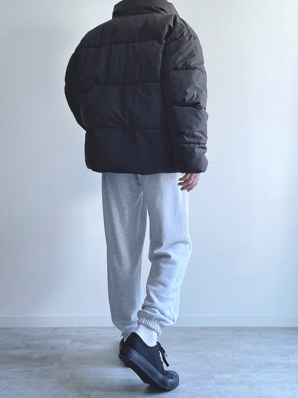 ブラック系のダウンジャケット/コート、イエロー系のトップス、グレー系のスウェットパンツを着用したメンズの冬コーディネートの3枚目の写真