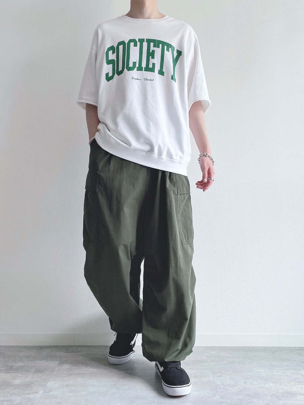 ホワイト系のTシャツ/カットソー、グリーン系のカーゴパンツ、ブラック系のスニーカーを着用したメンズの夏コーディネートの2枚目の写真
