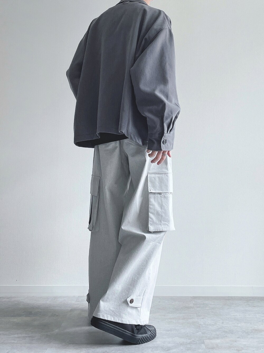 グレー系のブルゾン、ブラック系のトップス、ホワイト系のカーゴパンツを着用したメンズの春コーディネートの3枚目の写真