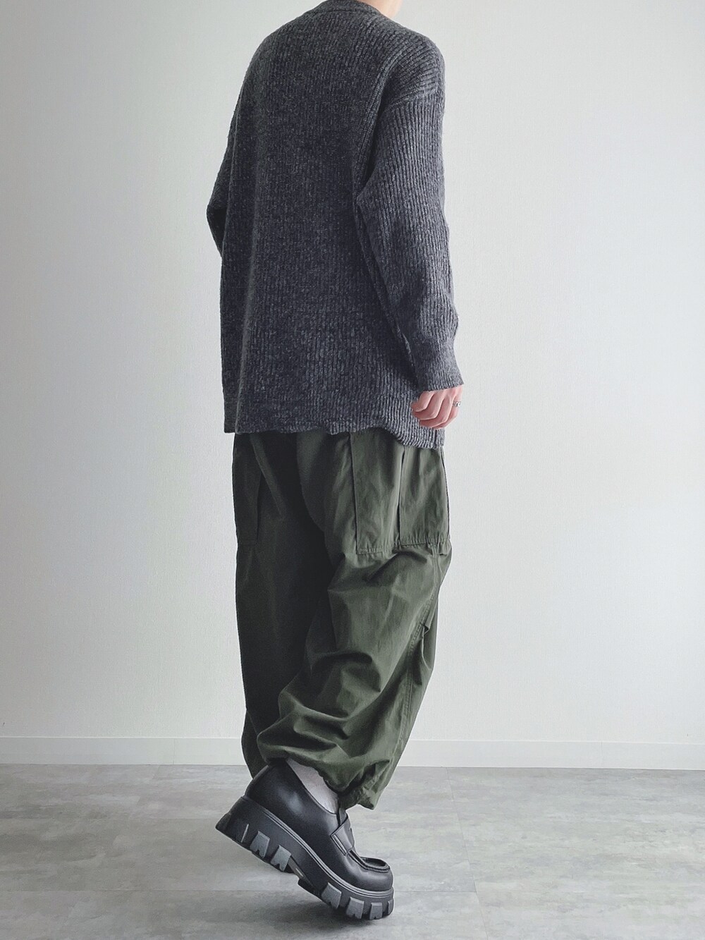 グレー系のニット/セーター、グリーン系のカーゴパンツ、ブラック系のローファーを着用したメンズの秋コーディネートの3枚目の写真