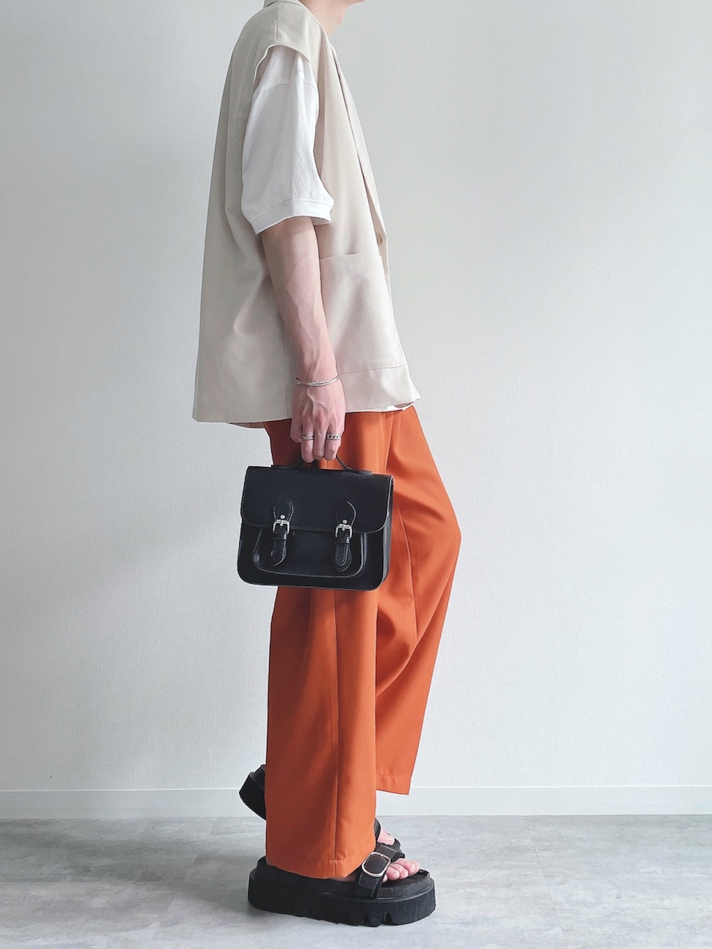 ホワイト系のベスト、ホワイト系のTシャツ/カットソー、オレンジ系のスラックスを着用したメンズの夏コーディネートの2枚目の写真