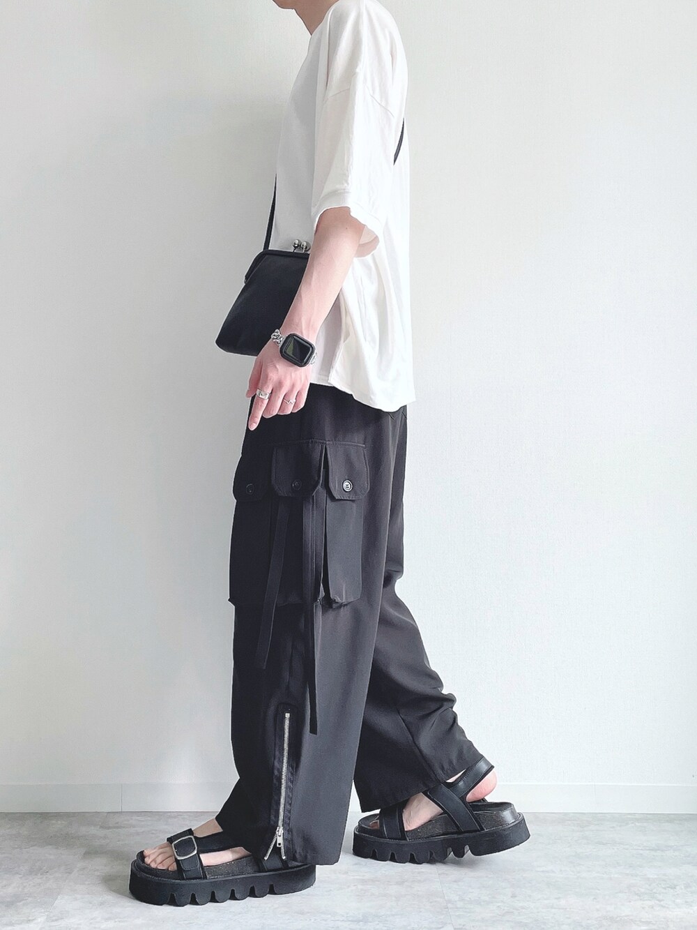 ホワイト系のTシャツ/カットソー、ブラック系のカーゴパンツ、ブラック系のサンダルを着用したメンズの春コーディネートの2枚目の写真