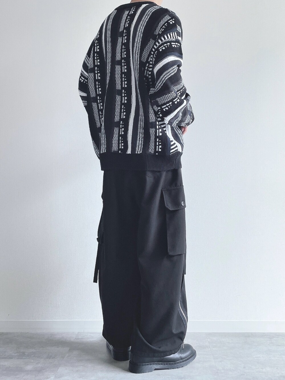 ブラック系のニット/セーター、ブラック系のカーゴパンツ、ブラック系のスニーカーを着用したメンズの秋コーディネートの4枚目の写真