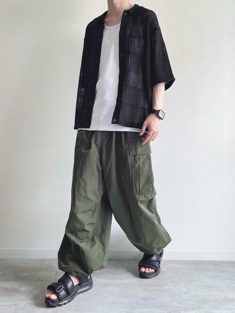 ブラック系のトップス、ホワイト系のタンクトップ、グリーン系のカーゴパンツを着用したメンズの春コーディネートの5枚目の写真