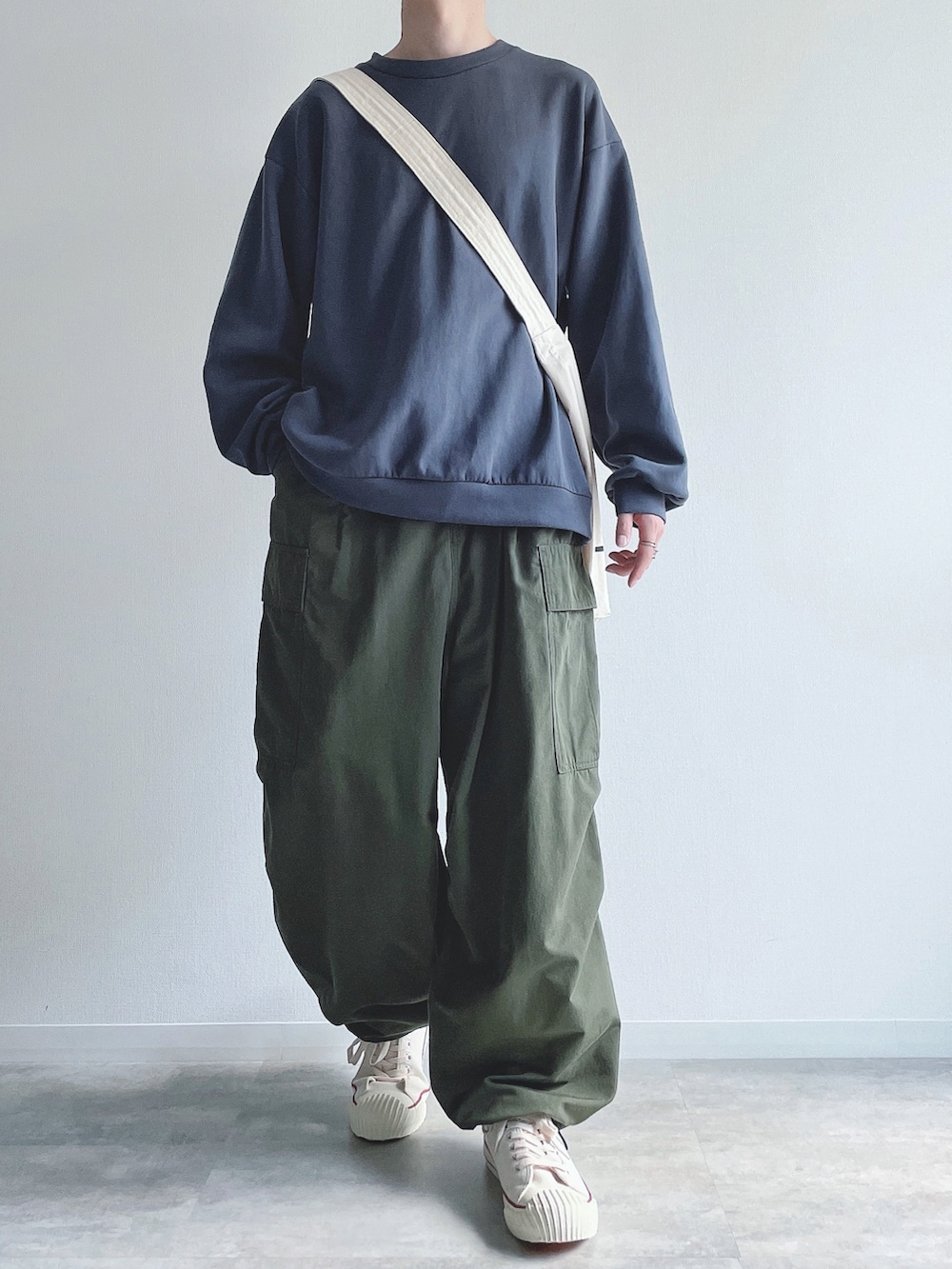 ブルー系のトップス、グリーン系のカーゴパンツ、ホワイト系のスニーカーを着用したメンズの秋コーディネートの2枚目の写真