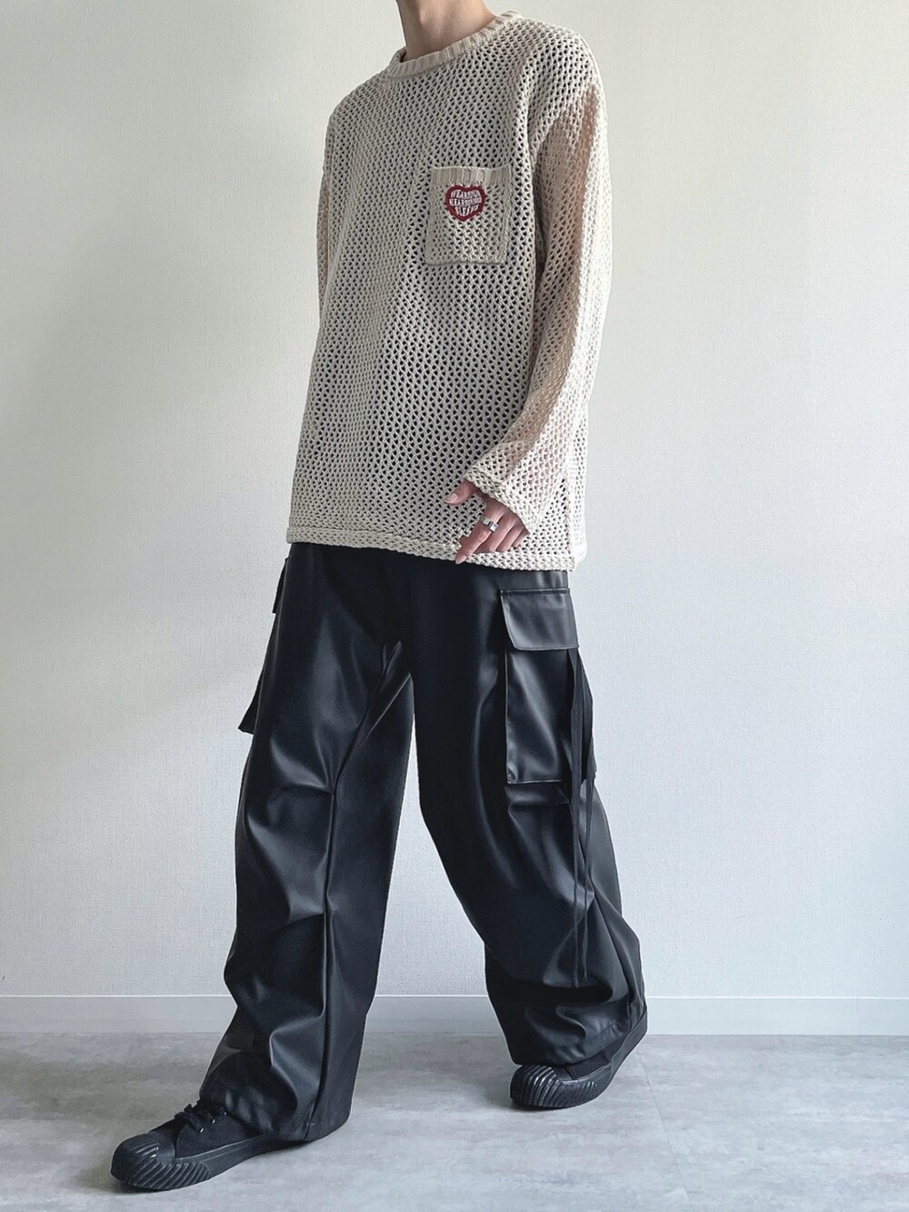 ホワイト系のニット/セーター、ブラック系のTシャツ/カットソー、ブラック系のカーゴパンツを着用したメンズの春コーディネートの5枚目の写真