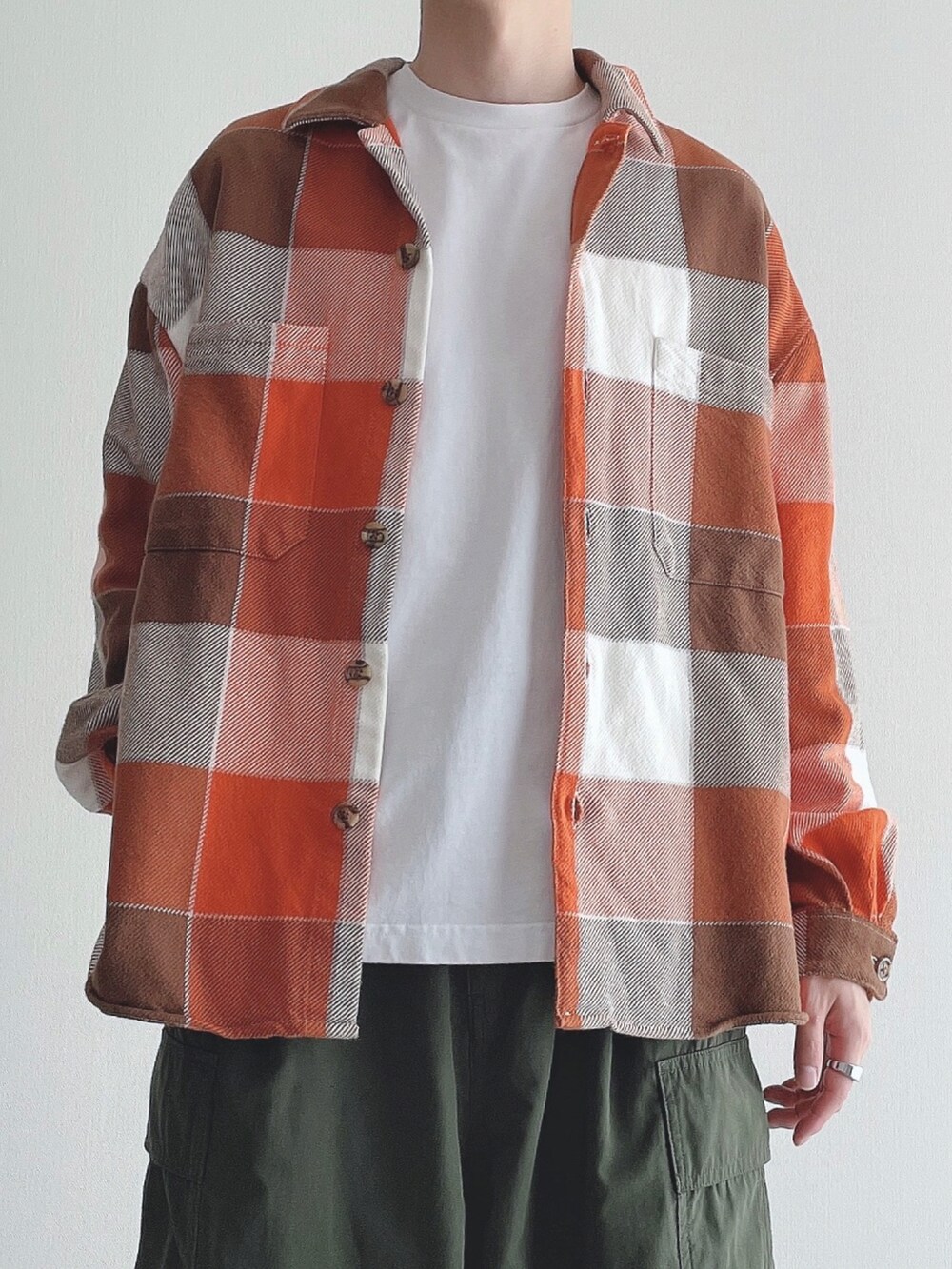 ホワイト系のTシャツ/カットソー、グリーン系のカーゴパンツ、ブラック系のスニーカーを着用したメンズの秋コーディネートの4枚目の写真