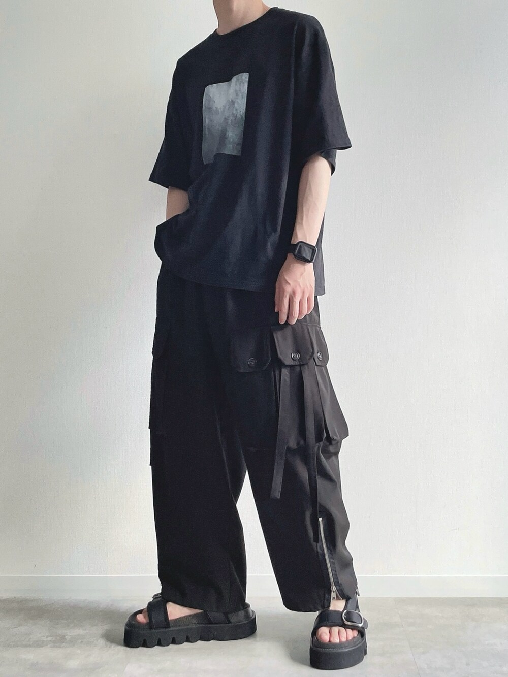 ブラック系のTシャツ/カットソー、ブラック系のカーゴパンツ、ブラック系のサンダルを着用したメンズの夏コーディネートの3枚目の写真