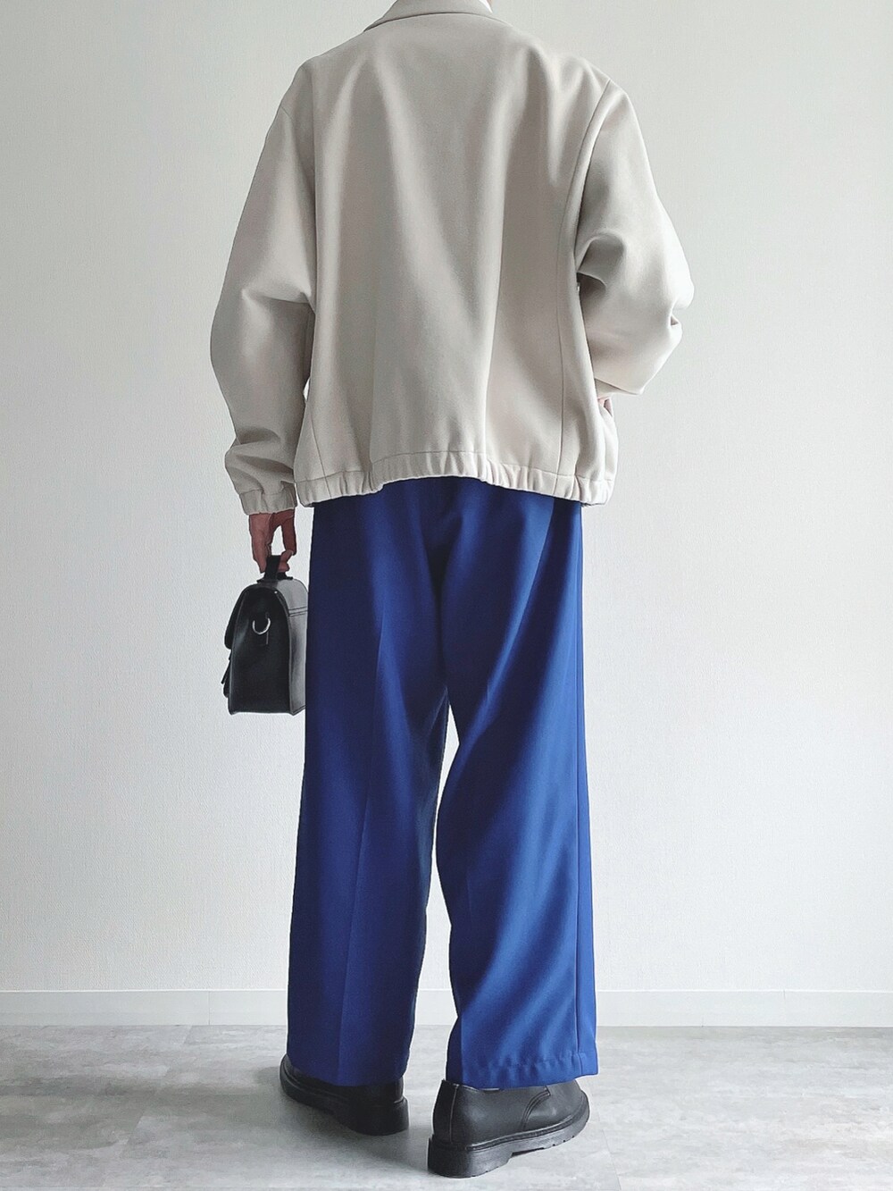 ホワイト系のブルゾン、ホワイト系のTシャツ/カットソー、ブルー系のスラックスを着用したメンズの冬コーディネートの3枚目の写真