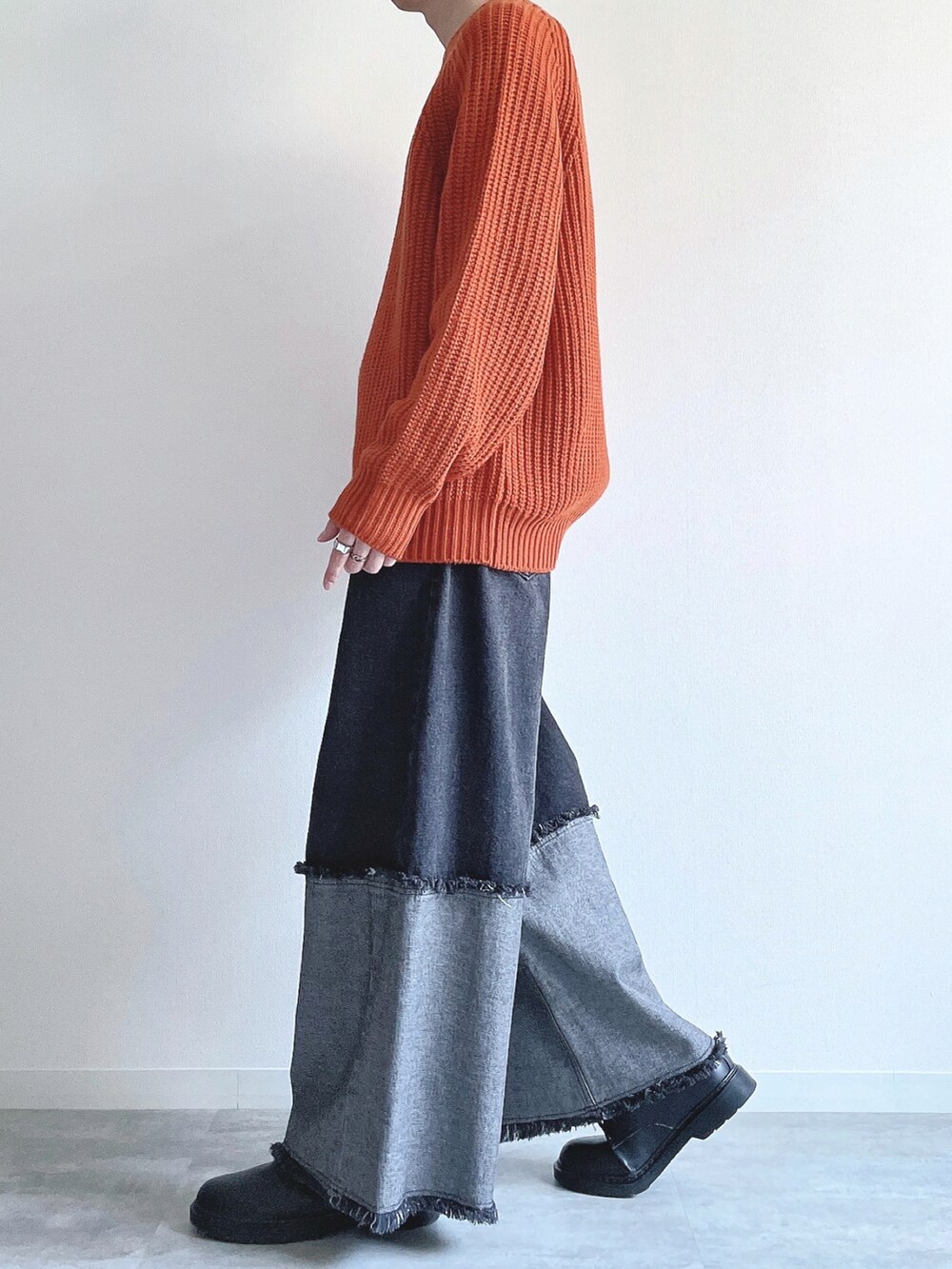 オレンジ系のトップス、ブラック系のデニムパンツ、ブラック系のスニーカーを着用したメンズの冬コーディネートの3枚目の写真