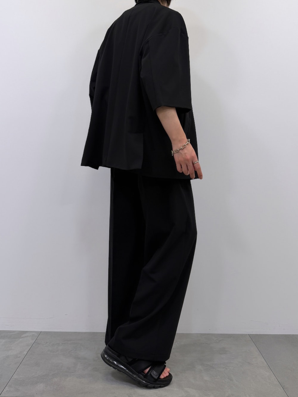ホワイト系のTシャツ/カットソー、ブラック系のセットアップ、ブラック系のサンダルを着用したメンズの春コーディネートの4枚目の写真