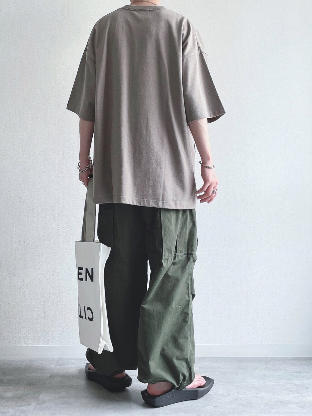 ベージュ系のTシャツ/カットソー、グリーン系のカーゴパンツ、ブラック系のサンダルを着用したメンズの夏コーディネートの3枚目の写真