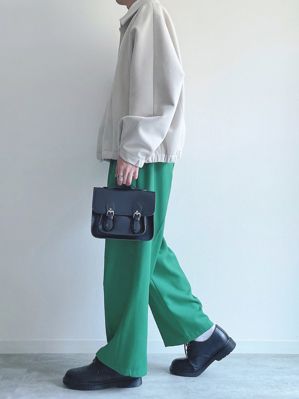 ホワイト系のブルゾン、ホワイト系のTシャツ/カットソー、グリーン系のスラックスを着用したメンズの春コーディネートの3枚目の写真