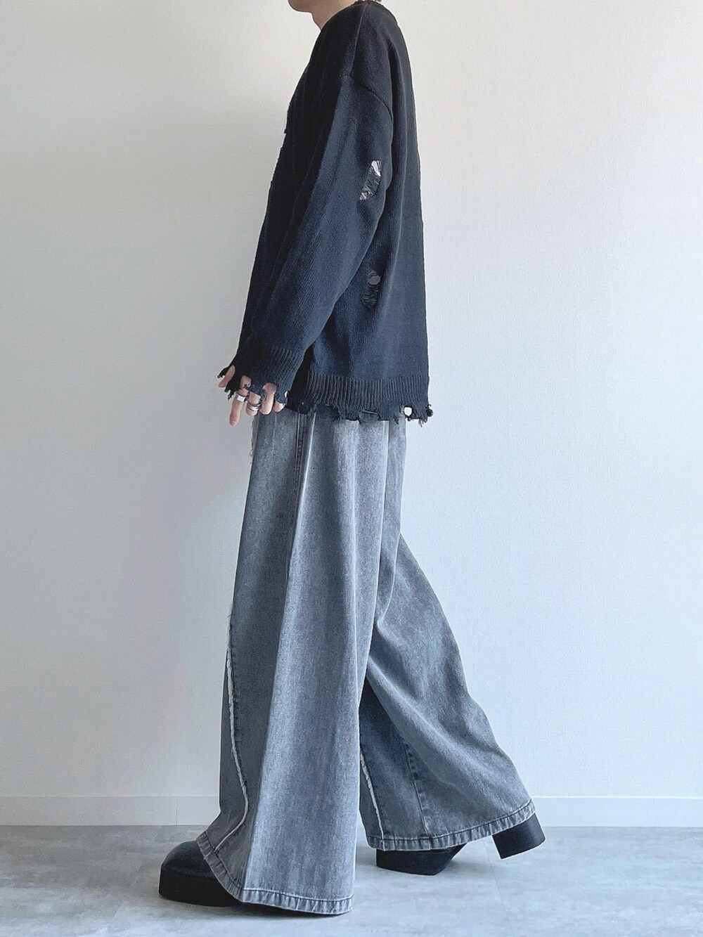 ブラック系のニット/セーター、ホワイト系のTシャツ/カットソー、グレー系のデニムパンツを着用したメンズの冬コーディネートの3枚目の写真