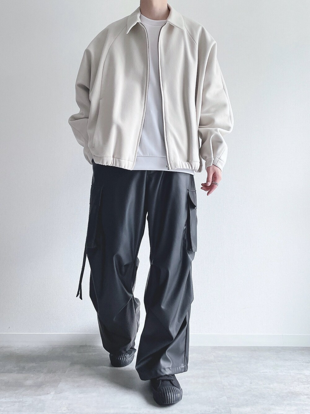 ホワイト系のブルゾン、ホワイト系のトップス、ブラック系のカーゴパンツを着用したメンズの冬コーディネートの2枚目の写真