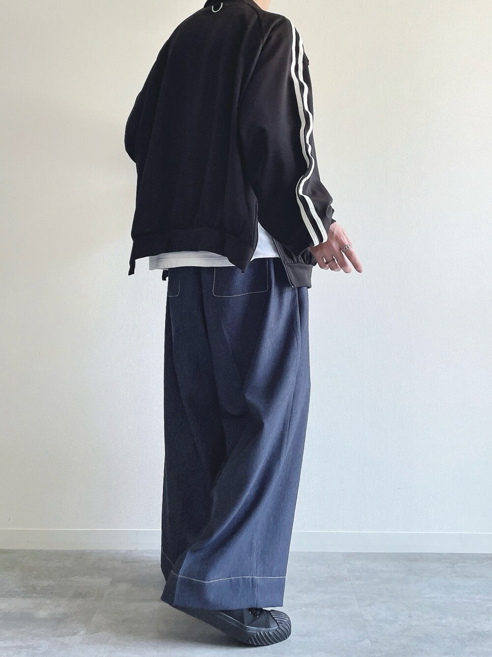 ブラック系のブルゾン、ホワイト系のTシャツ/カットソー、ブルー系のデニムパンツを着用したメンズの春コーディネートの4枚目の写真