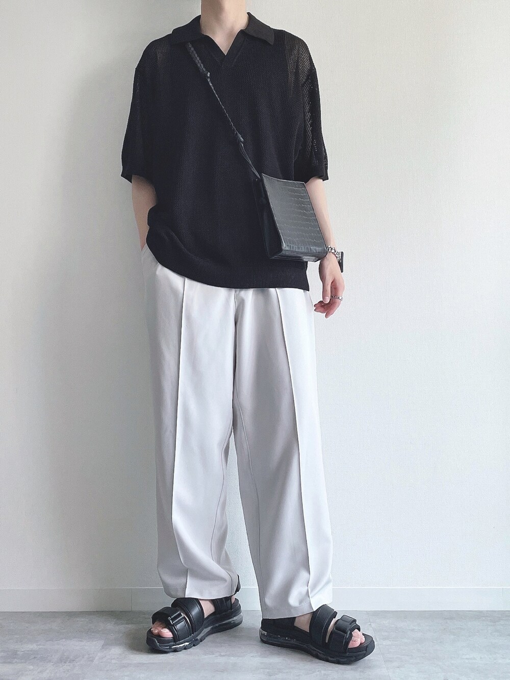 ブラック系のトップス、ホワイト系のスラックス、ブラック系のサンダルを着用したメンズの夏コーディネートの2枚目の写真