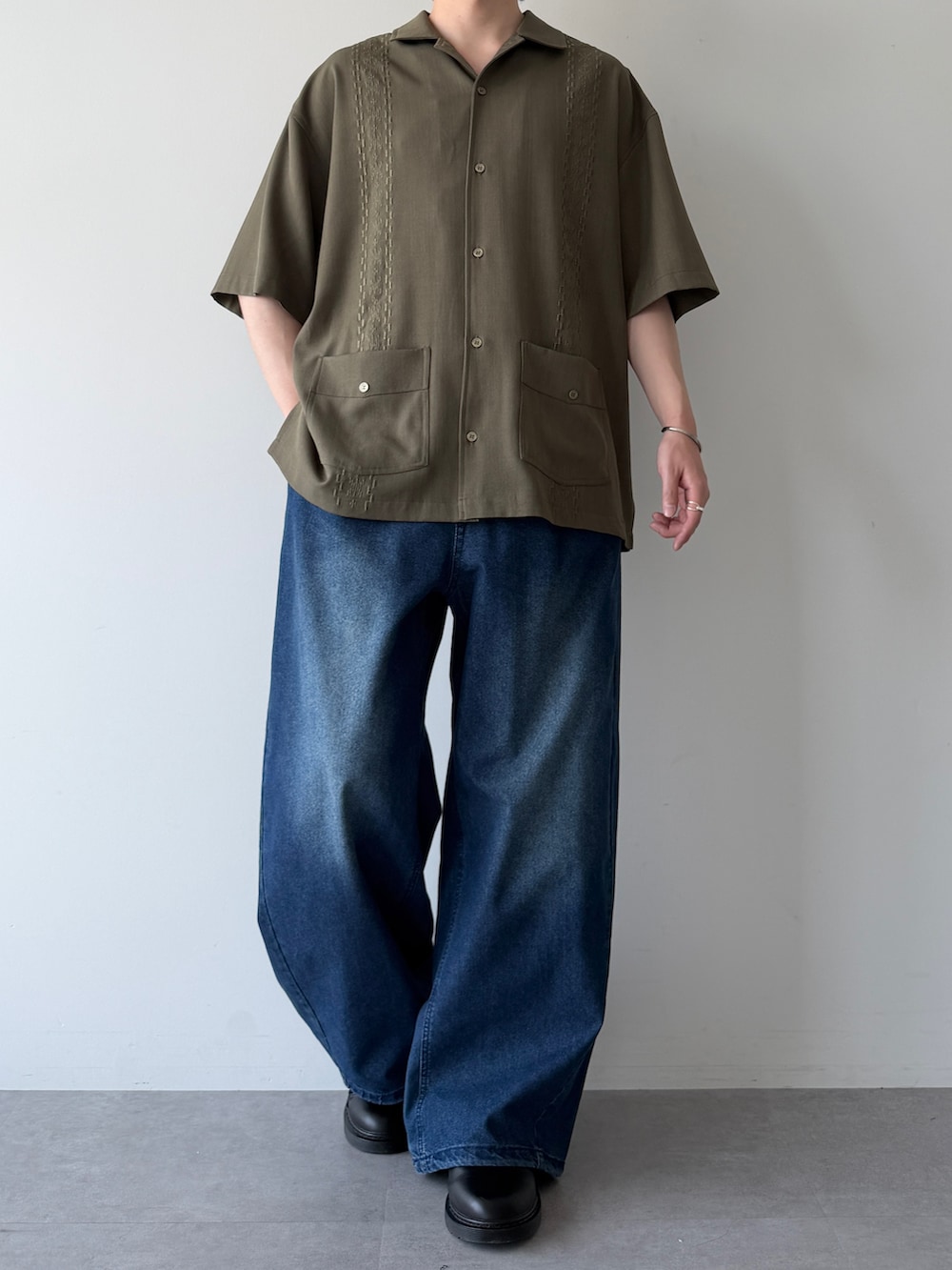 グリーン系のシャツ/ブラウス、ブルー系のデニムパンツ、ブラック系のシューズを着用したメンズの春コーディネートの2枚目の写真