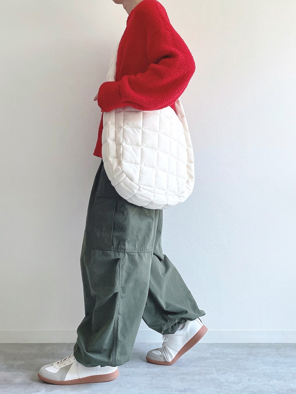 レッド系のニット/セーター、グリーン系のカーゴパンツ、ホワイト系のスニーカーを着用したメンズの冬コーディネートの3枚目の写真