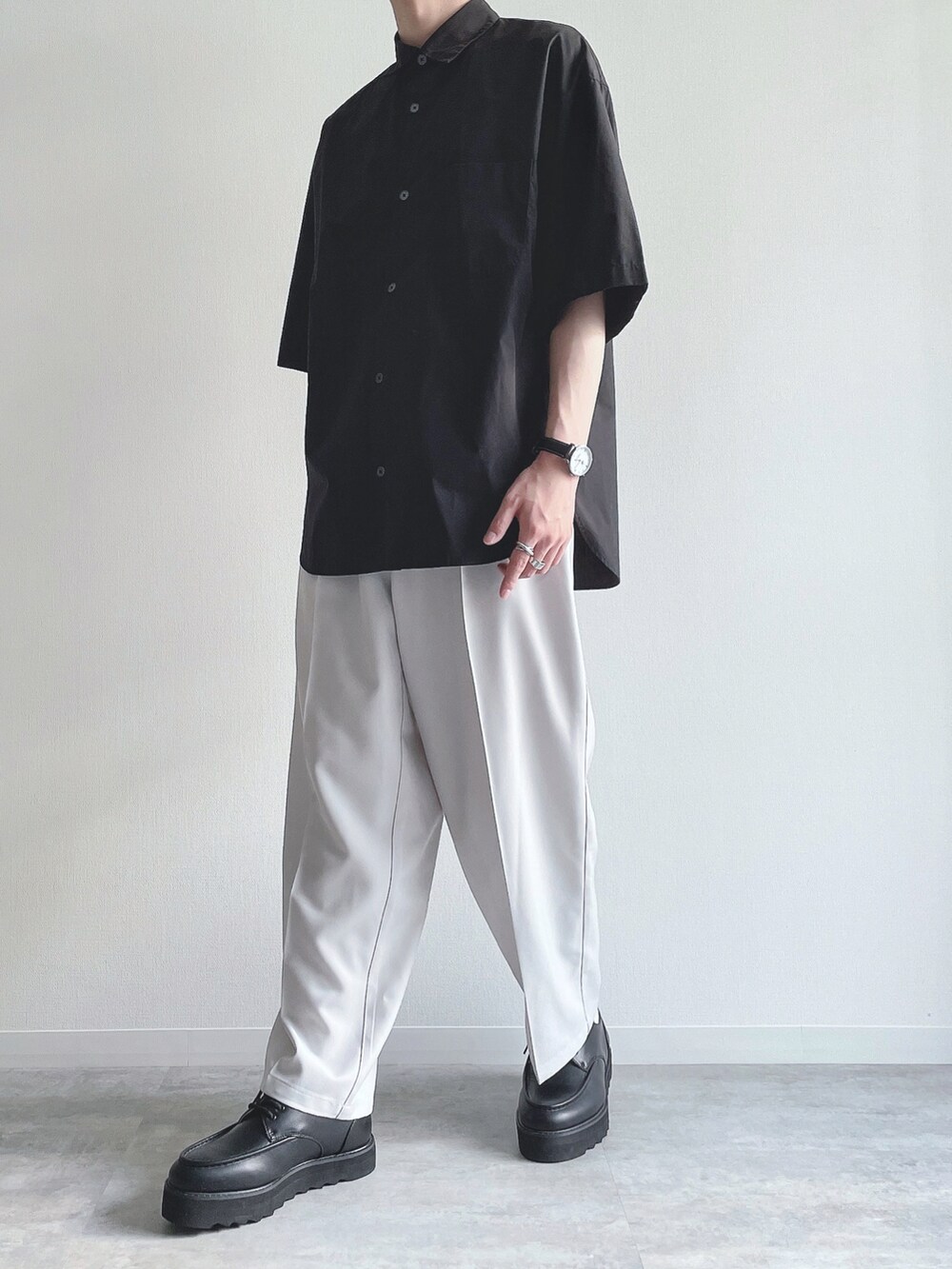ブラック系のトップス、ホワイト系のスラックス、ブラック系のモカシン/デッキシューズを着用したメンズの夏コーディネートの4枚目の写真