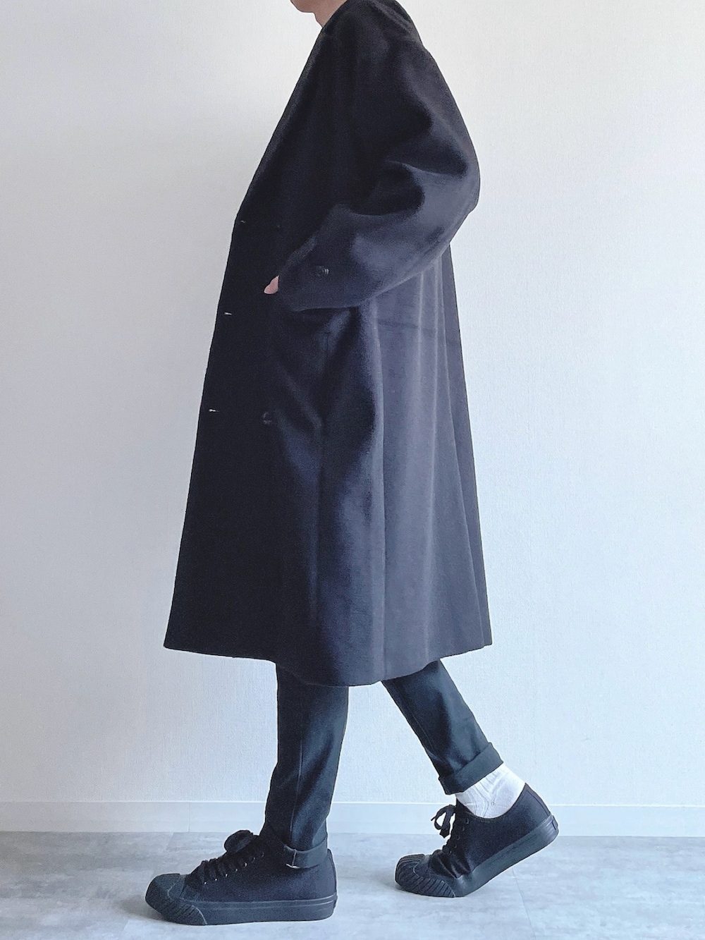 ブラック系のチェスターコート、ホワイト系のトップス、ブラック系のパンツを着用したメンズの冬コーディネートの2枚目の写真