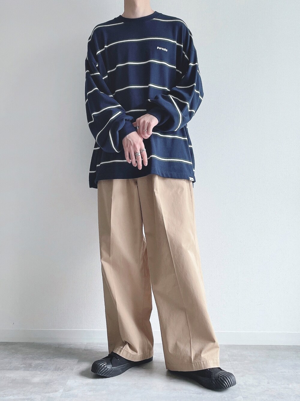 ブルー系のTシャツ/カットソー、ベージュ系のチノパンツ、ブラック系のスニーカーを着用したメンズの秋コーディネートの5枚目の写真