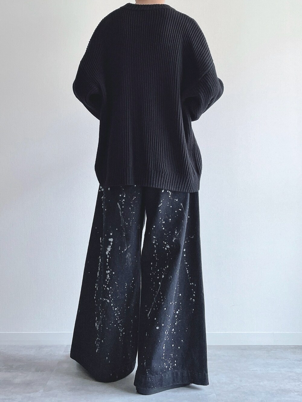 ブラック系のニット/セーター、ブラック系のデニムパンツ、ブラック系のスニーカーを着用したメンズの春コーディネートの4枚目の写真