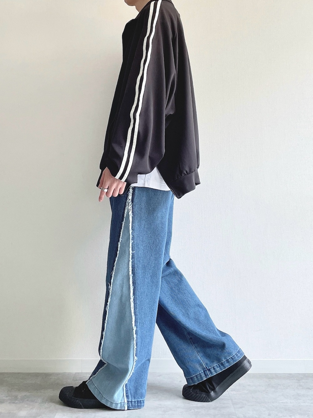 ブラック系のブルゾン、ホワイト系のTシャツ/カットソー、ブルー系のデニムパンツを着用したメンズの秋コーディネートの3枚目の写真