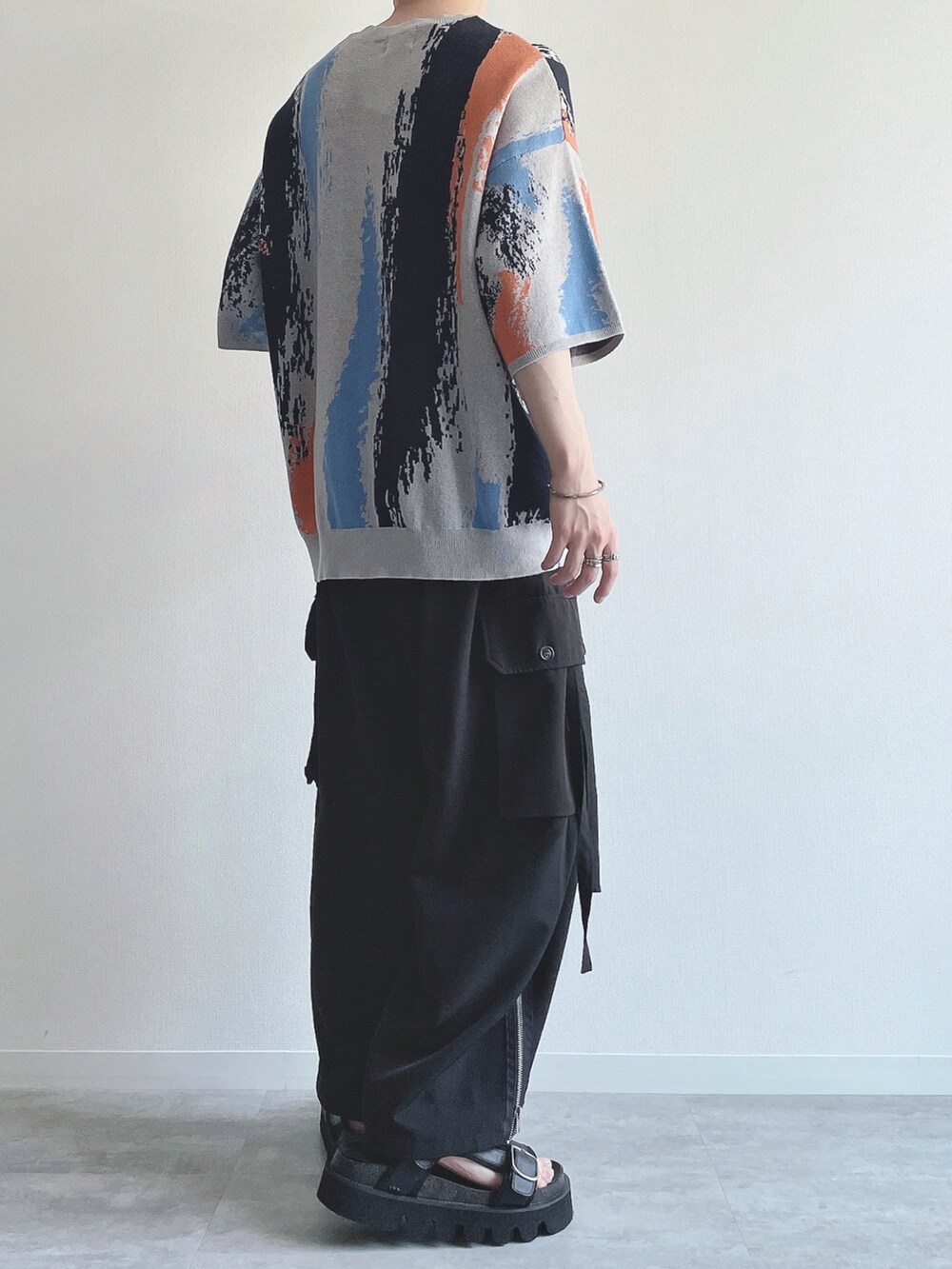 グレー系のニット/セーター、ブラック系のカーゴパンツ、ブラック系のサンダルを着用したメンズの夏コーディネートの3枚目の写真