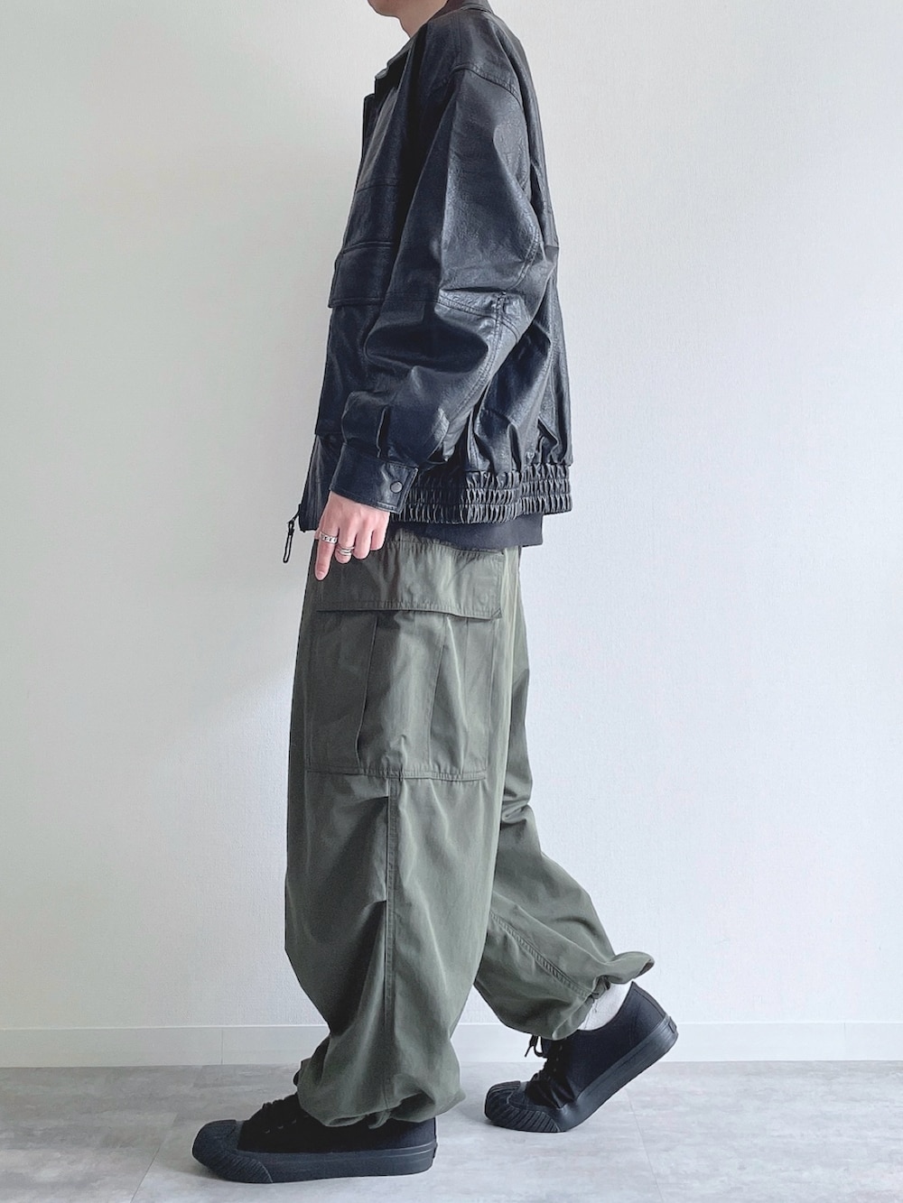 ブラック系のブルゾン、ブラック系のスウェット、グリーン系のカーゴパンツを着用したメンズの冬コーディネートの3枚目の写真