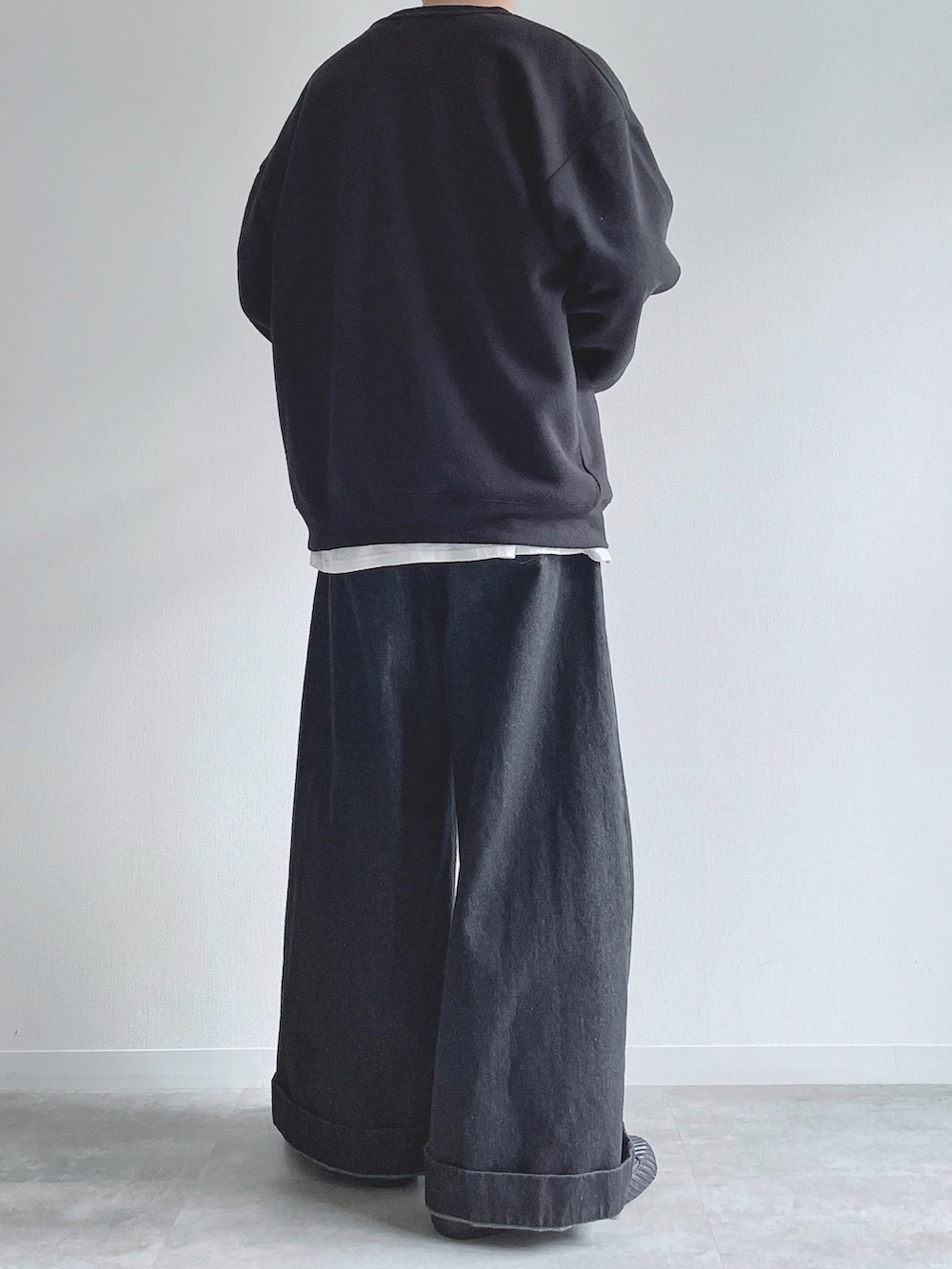 ブラック系のスウェット、ホワイト系のTシャツ/カットソー、ブラック系のデニムパンツを着用したメンズの冬コーディネートの3枚目の写真