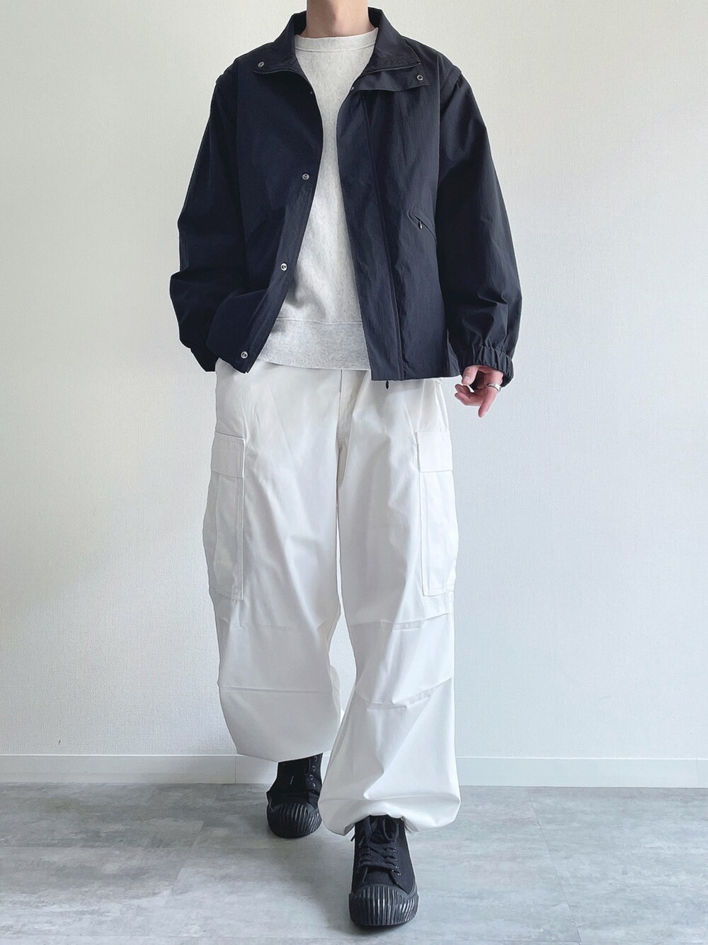 ブラック系のブルゾン、グレー系のトップス、ホワイト系のパンツを着用したメンズの春コーディネートの2枚目の写真