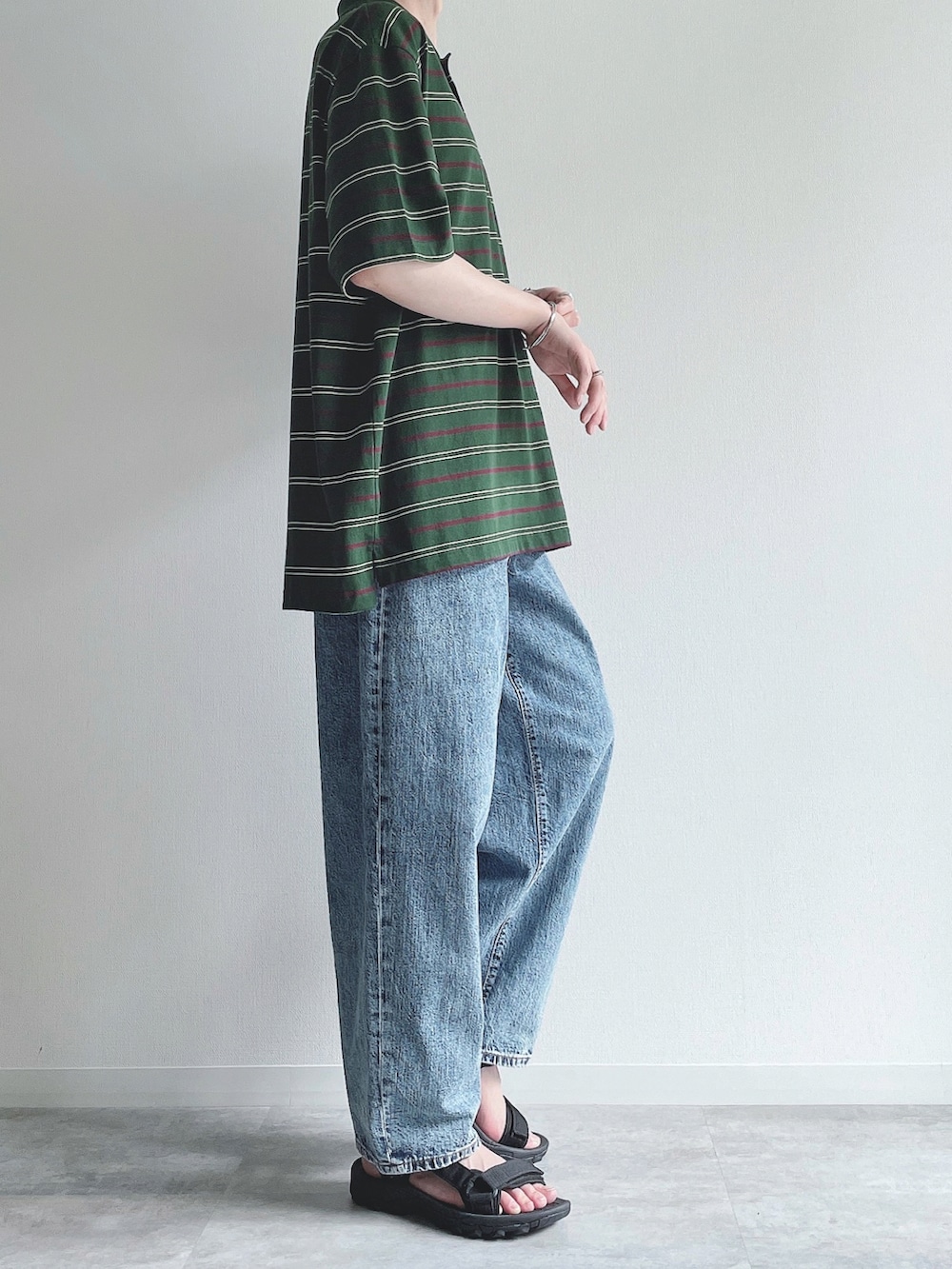 グリーン系のトップス、ブルー系のパンツ、ブラック系のサンダルを着用したメンズの夏コーディネートの2枚目の写真