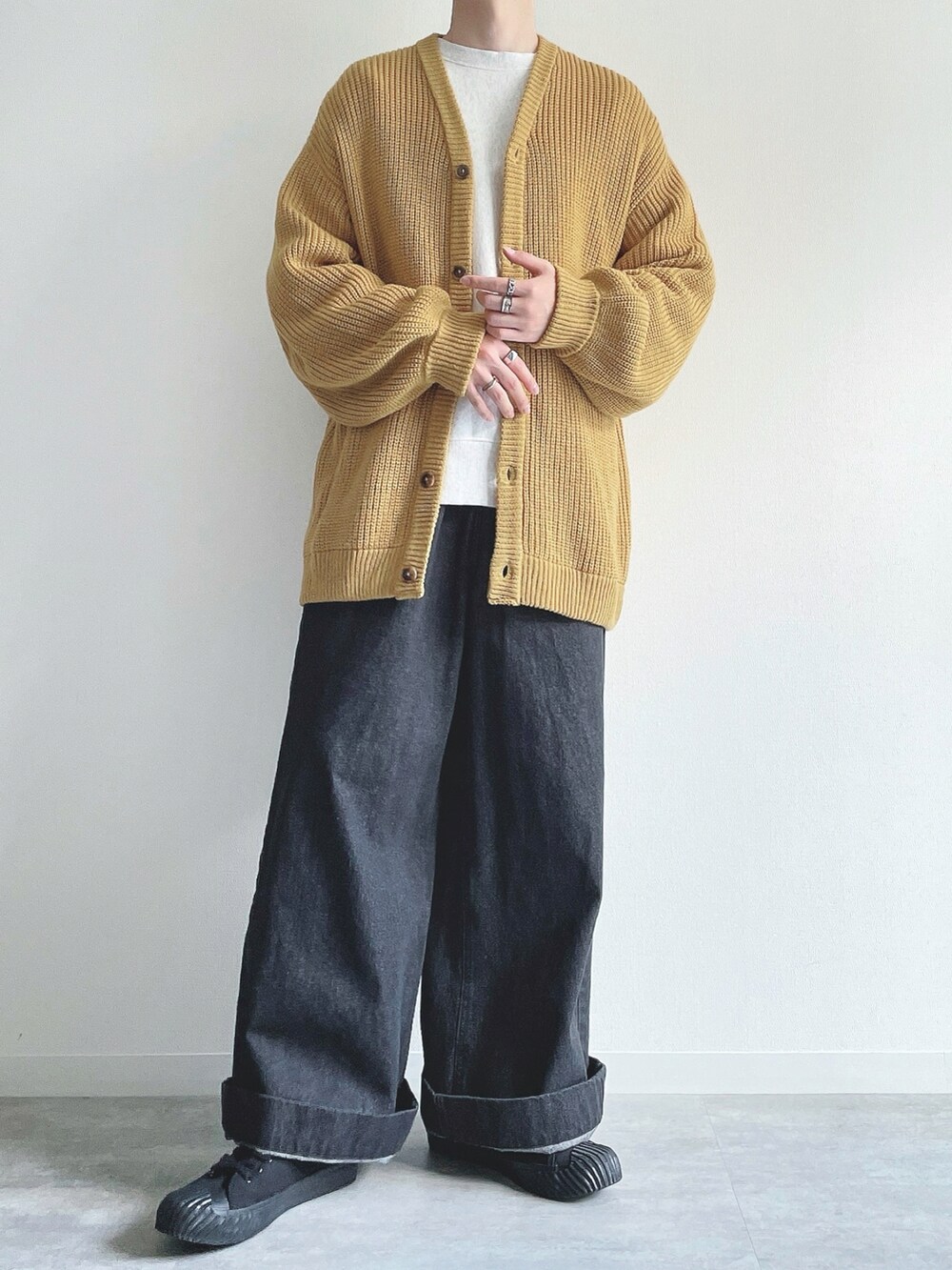 イエロー系のカーディガン/ボレロ、グレー系のトップス、ブラック系のデニムパンツを着用したメンズの秋コーディネートの5枚目の写真