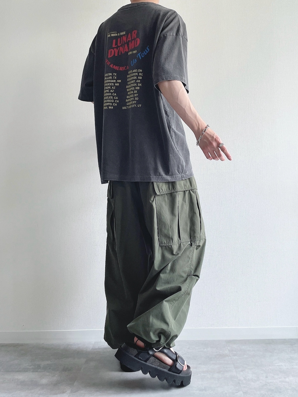 グレー系のTシャツ/カットソー、グリーン系のカーゴパンツ、ブラック系のサンダルを着用したメンズの夏コーディネートの4枚目の写真