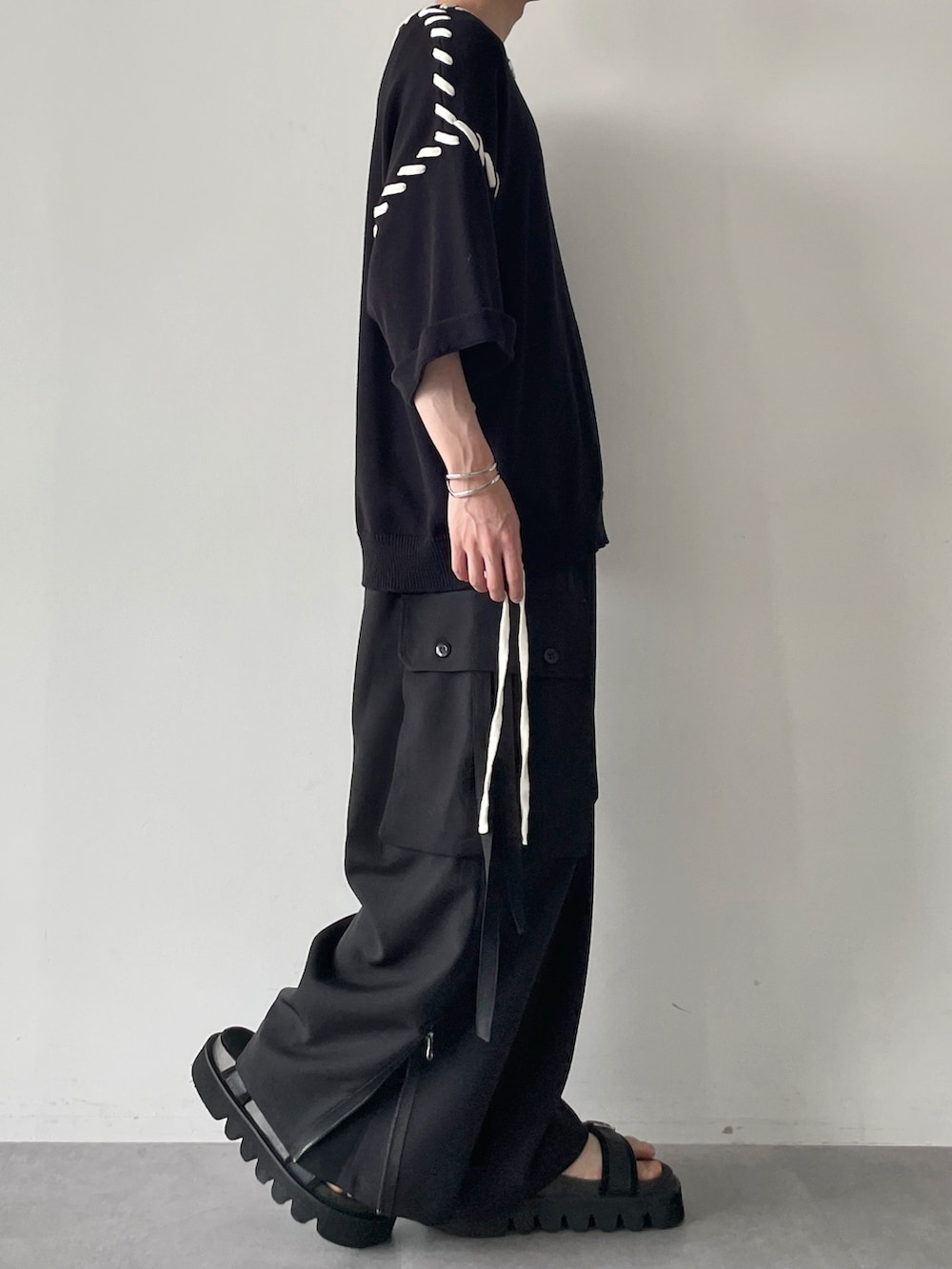 ブラック系のニット/セーター、ブラック系のその他パンツ、ブラック系のサンダルを着用したメンズの春コーディネートの3枚目の写真